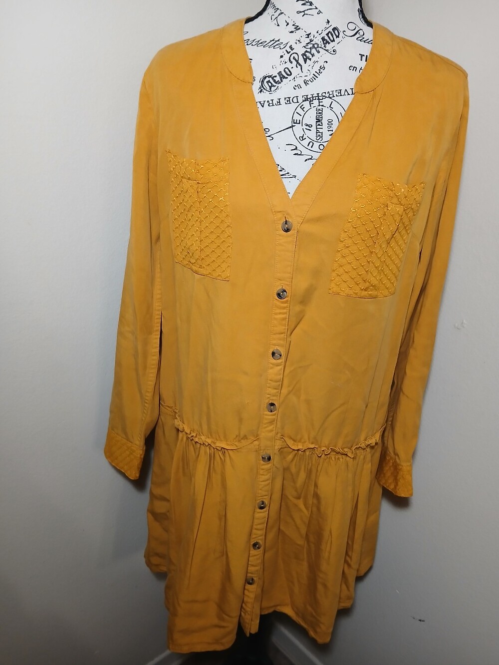 The Maeve Mustard Button-Front Tunic with Textured Chest Pockets has a small hol